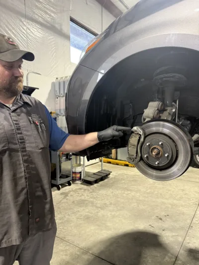 Mechanic pointing at brake pad wear indicator on a 2017 Toyota Sienna during inspection