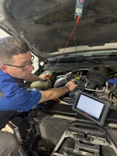 Mechanic performing engine diagnostics on a 2003 Chevrolet Silverado 2500 using diagnostic tools