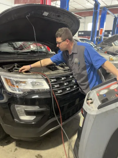 Mechanic servicing air conditioning system of a 2016 Ford Explorer during A/C maintenance